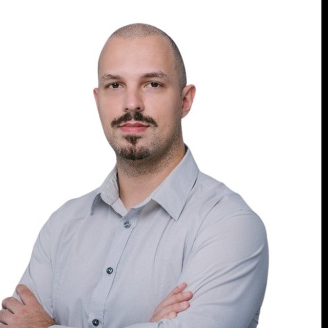 Tihomir, in a light grey-blue shirt, arms folded, looking at the camera